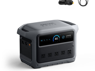 Anker portable power station with a display screen, four AC outlets, six USB ports, and Anker logo on the front. Above it are two cables: one car adapter and one standard charging cable.