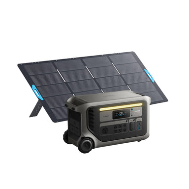 An Anker portable solar generator with a modern digital display and multiple outlets is placed in front of a foldable solar panel standing on two legs.