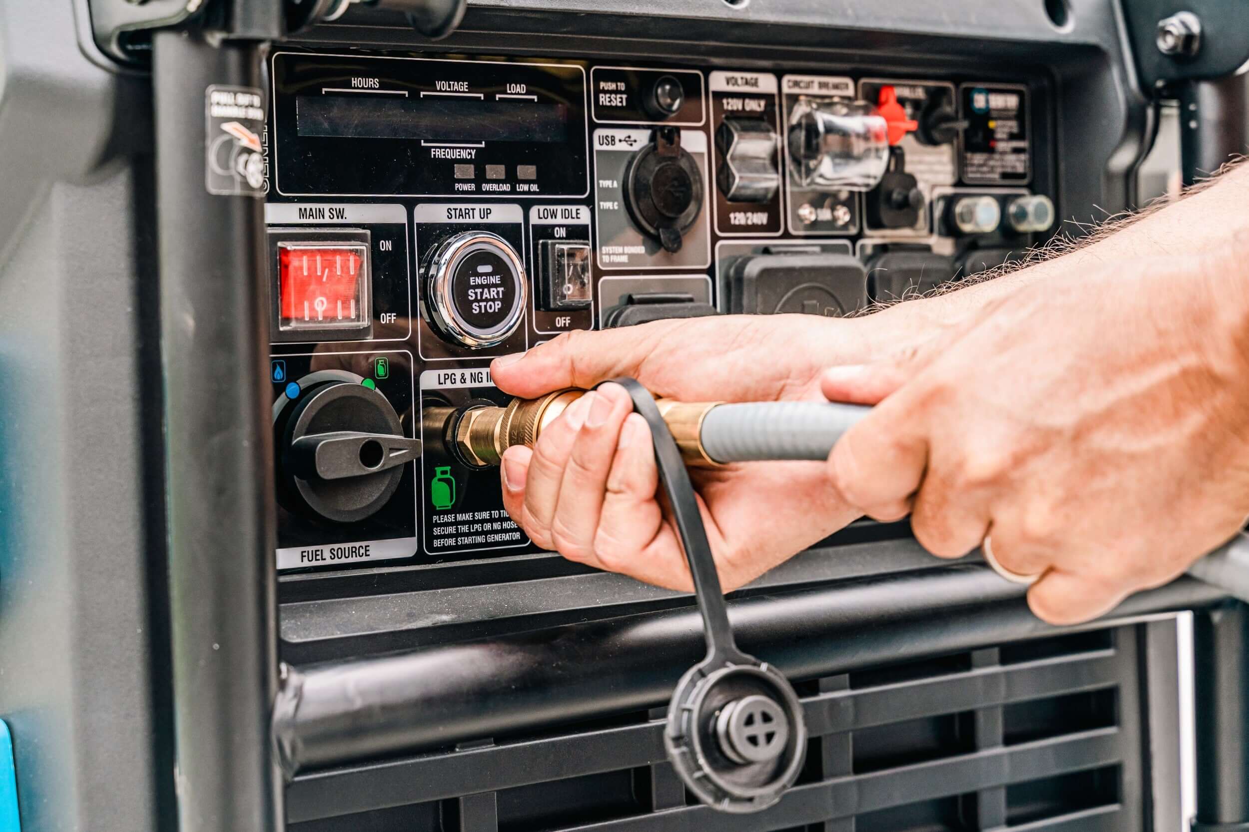 A person is connecting a hose to a Pulsar 10,500-watt tri-fuel inverter generator. Their focused attention is evident as they adjust a brass fitting on the control panel with one hand and steady the hose with the other, preparing for efficient power management.