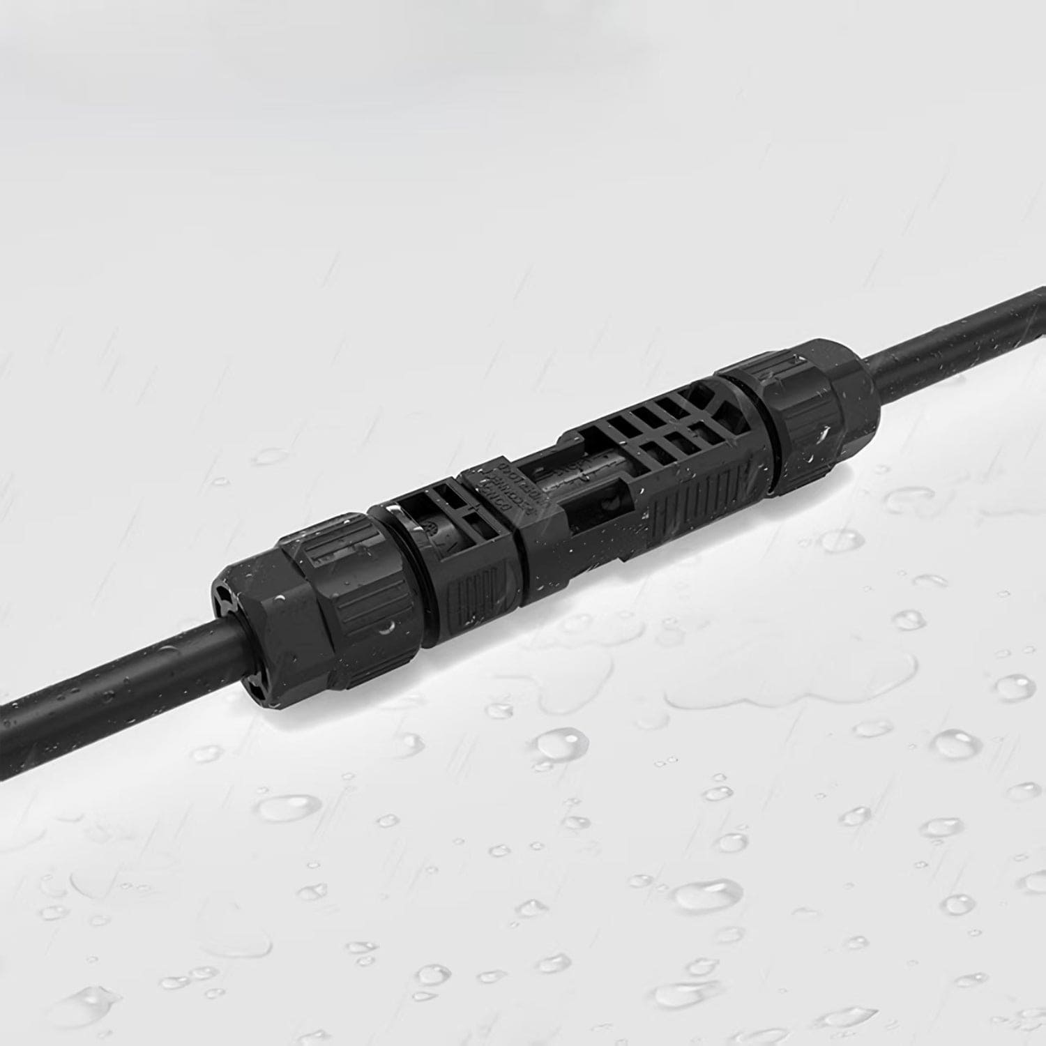 A close-up of a Nature's Generator black waterproof cable connector joining two MC4 extension cables, with water droplets on its surface highlighting its moisture resistance.