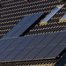 Close-up of black solar panels on a dark tiled roof with two rectangular windows nearby, aligned in two rows and powered by the Nature's Generator Lithium 3600 Pod, an advanced LiFePO4 battery expansion unit from Nature's Generator.