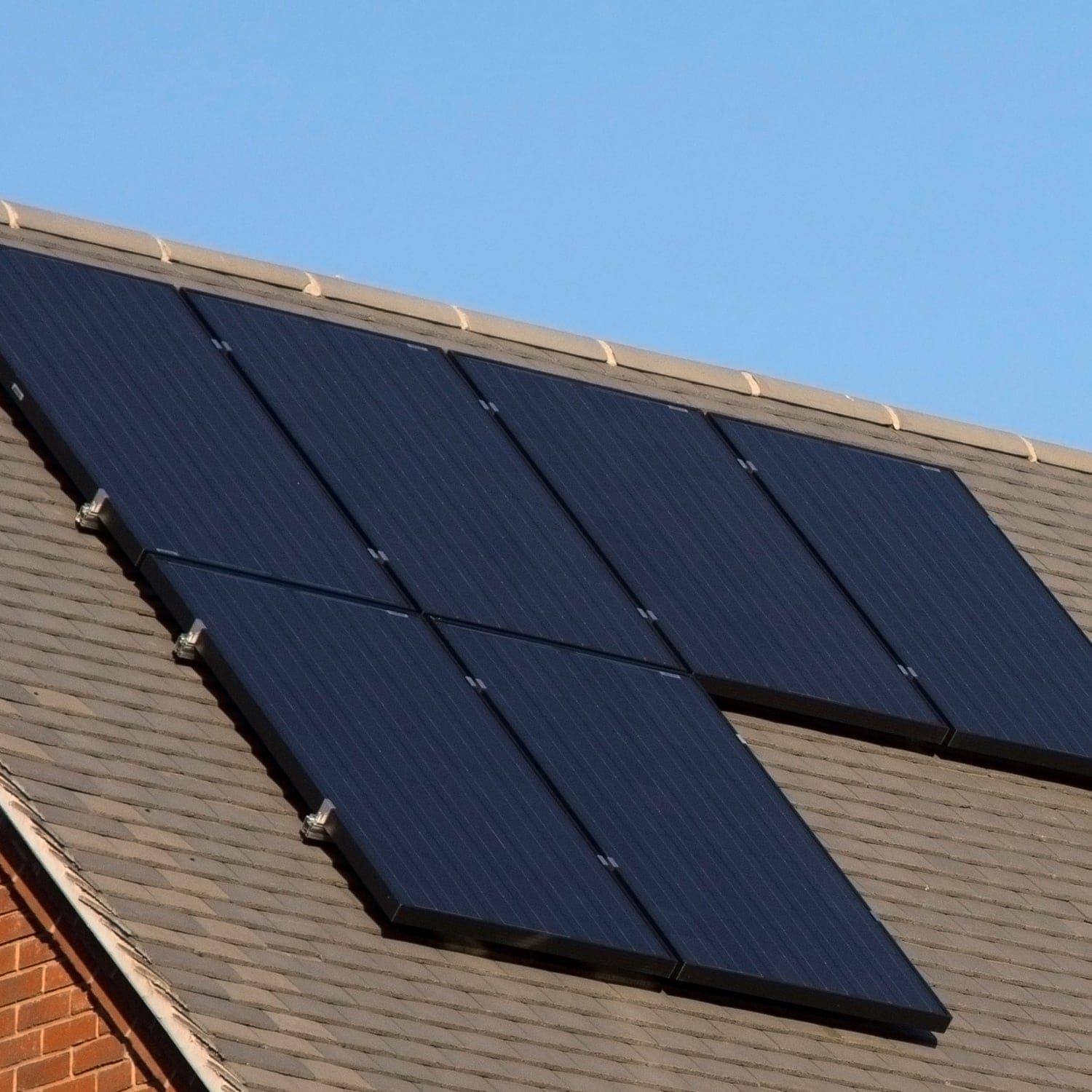 Eight Nature's Generator monocrystalline solar panels, each mounted securely on the sloped roof of a house, stand out against the clear blue sky.