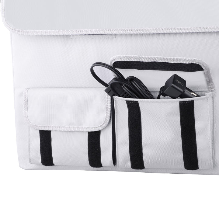 A white fabric organizer from ICECO Wholesale, adorned with black accents and multiple pockets, is perfect for storing accessories for your ICECO APL35 Portable Refrigerator. It includes a pocket with a coiled black cable and "Iceco" plug, another pocket with a flap, against a white surface background.