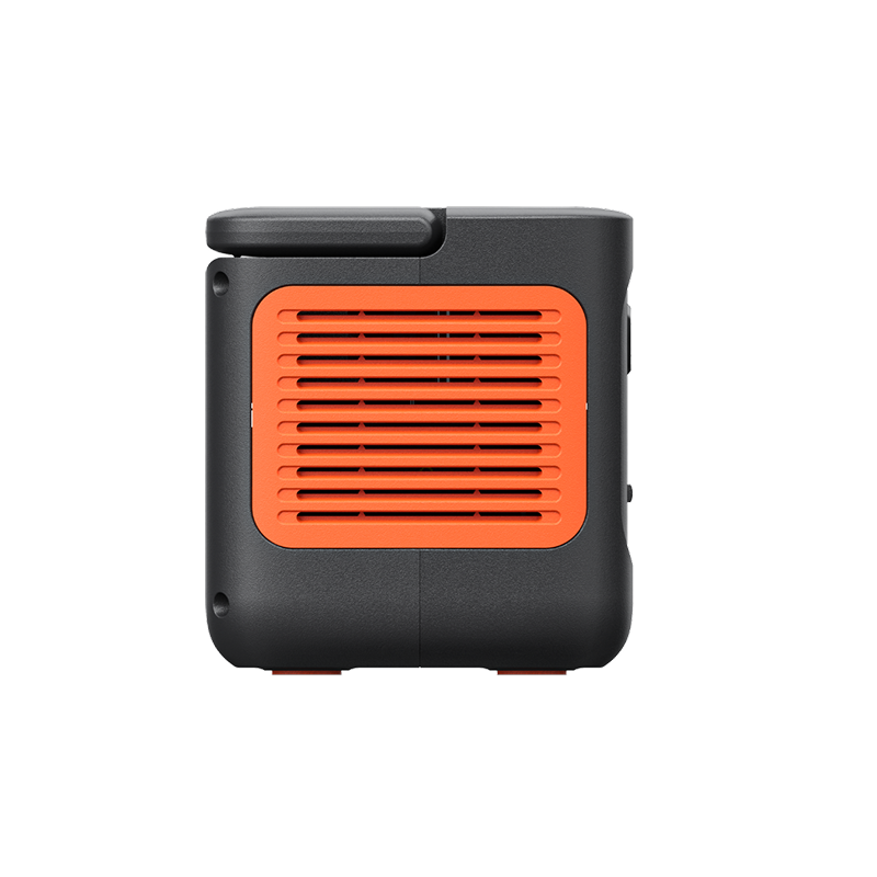 The Jackery portable power station is a compact, black device with an orange vented grille on one side and a raised section on the top left, shown against a white background—perfect for emergency backup power.