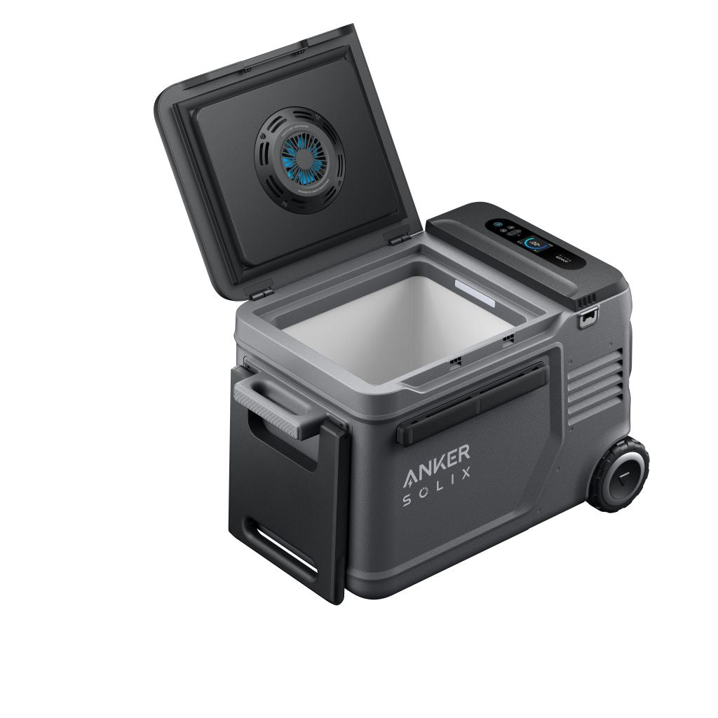 A portable rectangular Anker electric cooler with a hinged lid open, showing an empty interior. It includes a digital display, side handle, wheels, and an inside-lid vent.