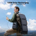 An outdoor adventurer carries an Anker portable power station in one hand with a large solar panel on their backpack. Blue sky and clouds above, text highlights Anker's 100W solar recharging—perfect for off-grid adventures.