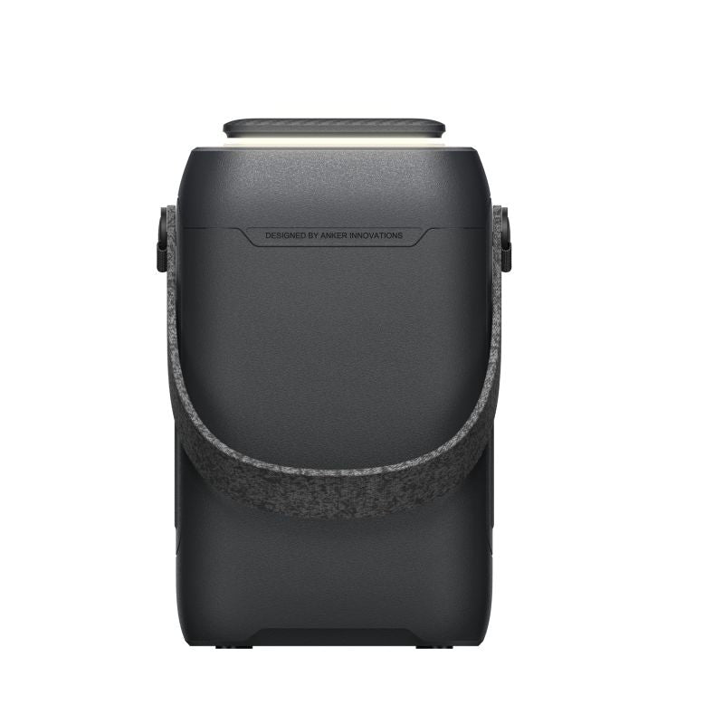 A black Anker portable speaker with a textured gray strap stands upright against a white background. Its smooth top surface features "Designed by Anker Innovations" near the top, reflecting minimalist design aesthetics.