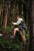 A hiker with an Anker cap, jacket, shorts, backpack, and trekking poles walks uphill through a dense forest of tall trees and green ferns. No product descriptions are found among the foliage—just CSS code and class definitions.
