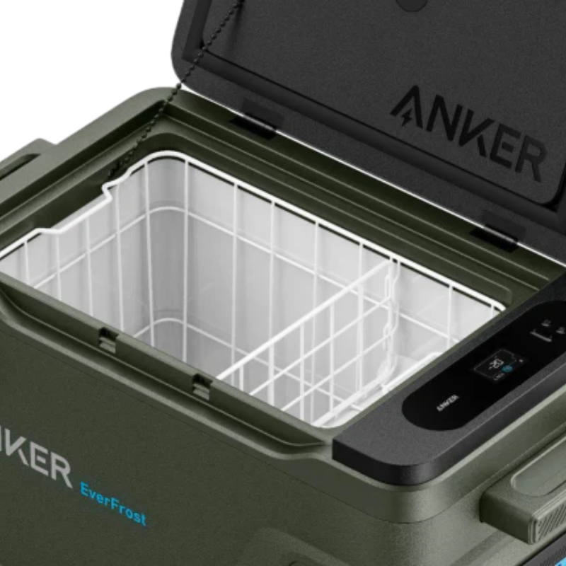 A close-up view of an Anker cooler, powered by a battery, with its lid open to show an empty white wire basket inside. The brand name "Anker" and model name "EverFrost" are clearly displayed on the lid and side.