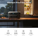 Anker 2kWh portable power station powers an open, lit fridge on a kitchen counter at dusk. Icons below show fridge, microwave, oven, and kettle usage times. Ultra-fast recharge feature included.