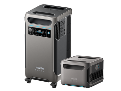 Two Anker portable power stations are displayed. The larger unit on the left, similar to the Anker SOLIX F3800 model, features a digital display and multiple ports, complete with small wheels for easy mobility. The smaller unit on the right has a more straightforward design. Both units are gray with futuristic accents and are ideal for integration with solar panels.