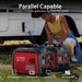 A person kneels beside two connected PowerSmart 3600W red inverter generators by an RV, showcasing their parallel capability. Text reads, “Parallel Capable—connect 2 inverter generators for double the power.” Compatible device icons shown.