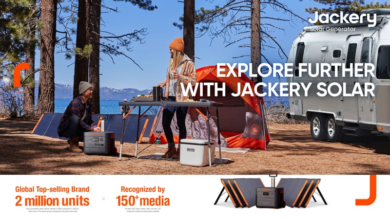 Two individuals are camping near a lakeside surrounded by trees, with an Airstream trailer in the backdrop. A Jackery solar generator and solar panels are prominently displayed, highlighting their substantial capacity ideal for extended adventures. The text encourages readers to "Explore Further with Jackery Solar" and highlights the brand's sales success and media accolades.