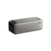 An Anker rectangular gray portable Bluetooth speaker is displayed against a white background, featuring a mesh front, side control buttons, blue power indicator light, and backup power for longer playtime.