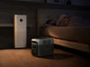 A man sleeps in bed at night. Beside him, a large air purifier and an EcoFlow DELTA 3 1500 Portable Power Station with a LiFePO4 battery sit on the floor, both powered on and showing digital displays.