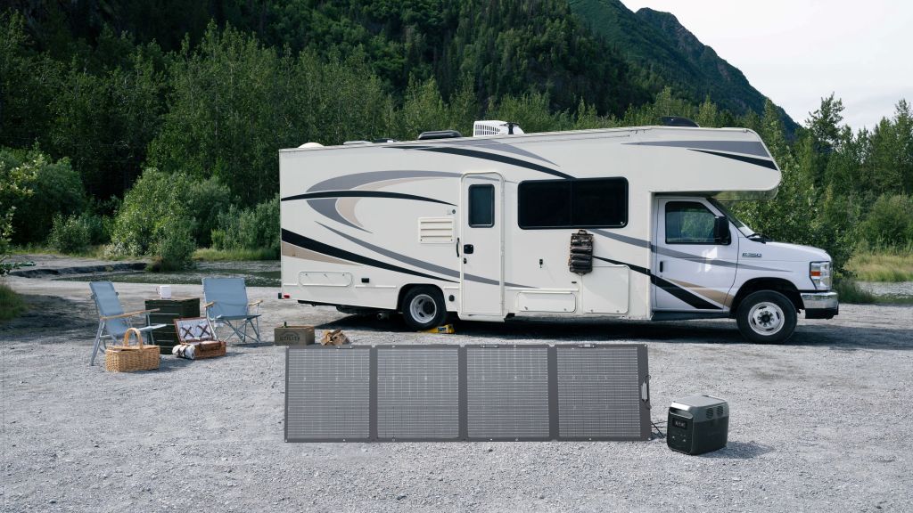 A white camper van is parked on gravel by trees and hills. Up front, foldable solar panels charge an EcoFlow DELTA 3 1500 Portable Power Station (LiFePO4 battery), providing backup power for the camping chairs, table, and picnic basket beside the van.