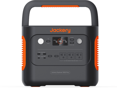 The Jackery portable power station features a digital display and multiple outlets, including AC, USB, and DC ports. Its black design includes orange accents and an integrated top handle for easy carrying.