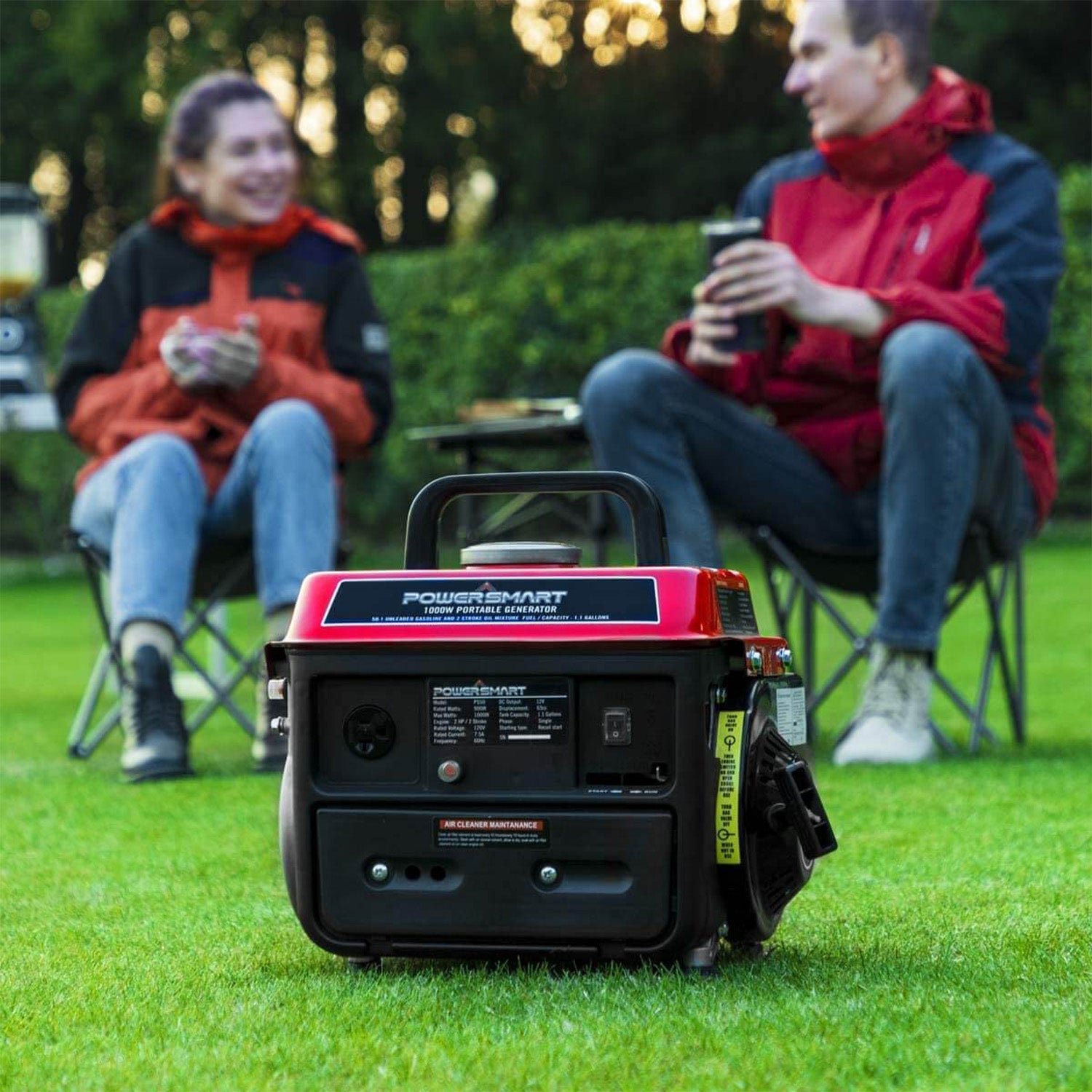 A red and black PowerSmart portable generator sits on the grass, supplying camping power, as two people in jackets relax with mugs on foldable chairs in front of lush greenery.