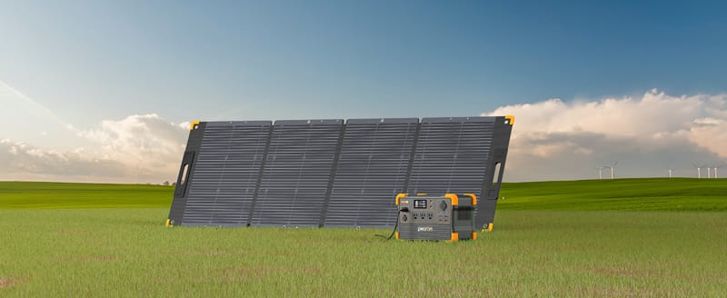 A Pecron solar panel and a portable power station featuring a Pecron E600LFP Pure Sine Wave Inverter are positioned in a grassy field under a clear blue sky. In the distance, wind turbines and the dependable Pecron LiFePO4 Battery enhance the sustainable landscape.