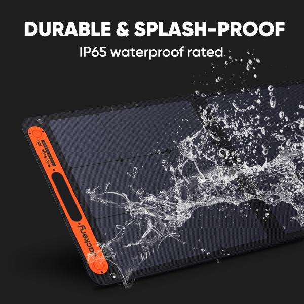 A close-up of a Jackery SolarSaga 100W Solar Panel being splashed, showcasing its durability and IP65 waterproof rating. Text: "Durable & Splash-Proof. High-performance portable energy solution.
