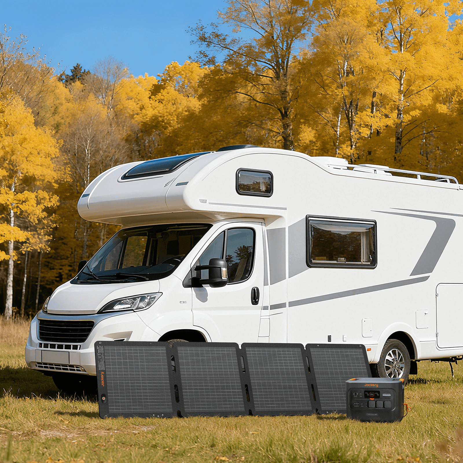 A white motorhome is parked on grass near yellow-leaved trees. In front, a Jackery 100Wair portable solar panel and power station from Jackery provide easy solar charging.