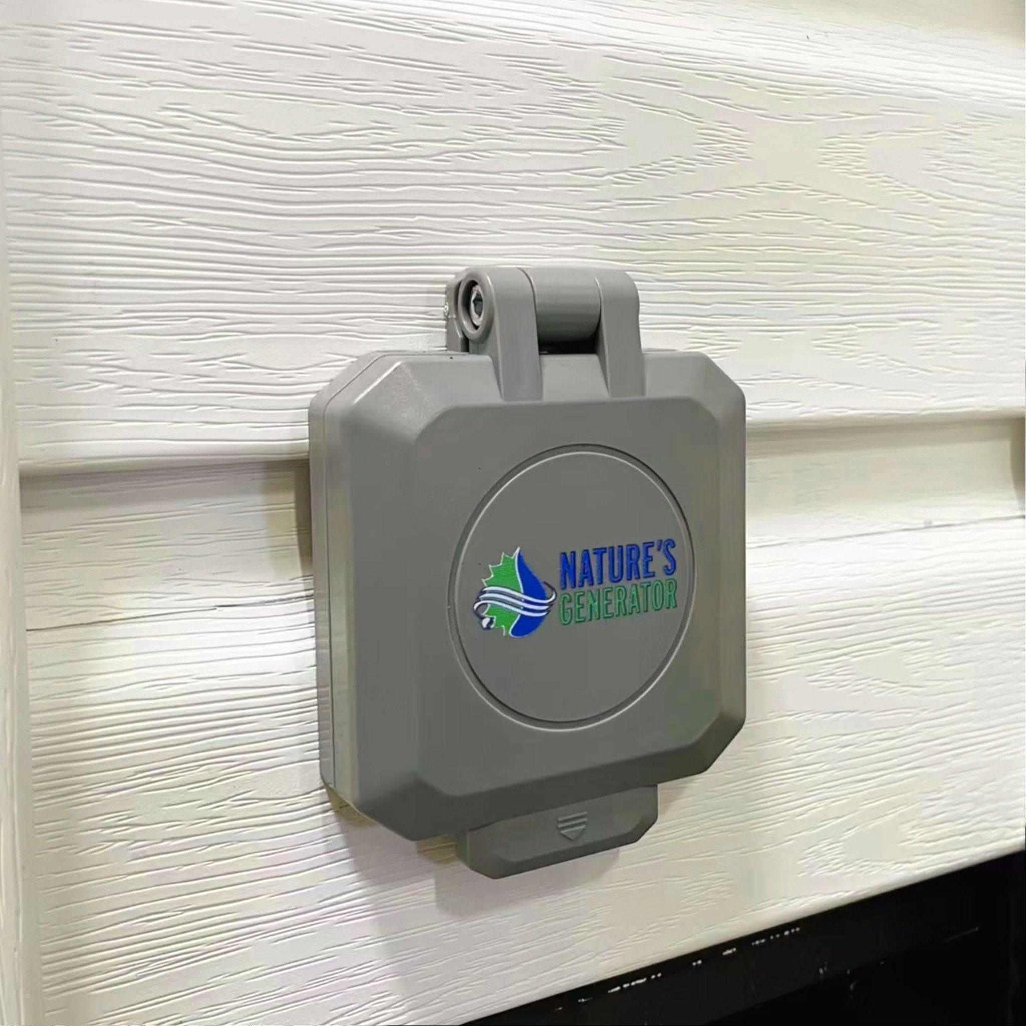 A gray, rectangular Nature's Generator outdoor power outlet cover is mounted on white textured siding. Its weatherproof design offers secure protection, making it ideal for a 50 Amp Generator Inlet Box installation.