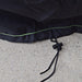 Close-up of a black 600D polyester fabric edge with green stitching from Nature's Generator, lying on concrete. A black drawstring with plastic toggle is threaded through the hem—ideal as a generator protective cover.