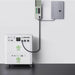 A portable Nature's Generator battery backup system labeled "Power House" and "Power Pod" connects to a wall-mounted panel via a thick cable, providing efficient home power backup in a clean indoor setting.