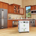 A Nature's Generator portable white home battery backup with control panels and wheels is positioned in a modern kitchen featuring wooden cabinets, stainless steel appliances, and a large window with an outdoor view.