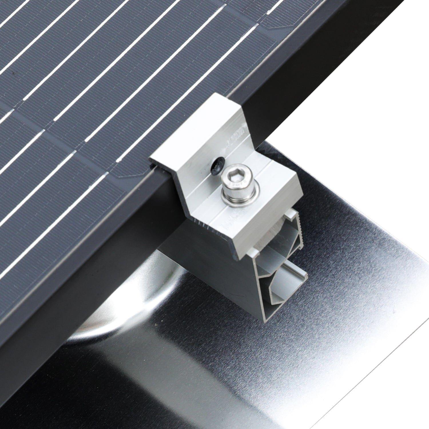 A close-up view of a Nature's Generator aluminum alloy solar mounting kit fastening a solar panel to a metal surface, displaying the panel frame, bracket, bolt, and underlying support structure.
