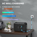 An ALLWEI US black 1008Wh LFP portable power station charges via an AC wall socket on a wooden desk. Text showcases AC wall charging and quick, normal, and silent recharge times. Nearby are a plant, books, and wireless earbuds.